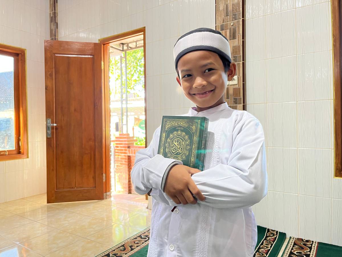 Young Muslim boy holding a copy of the Quran