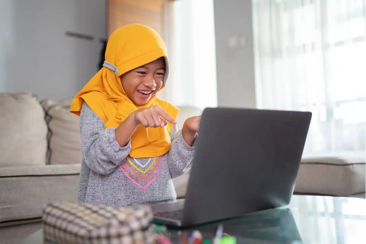 Young Muslim girl enjoying an online Quran lesson on a laptop at home
