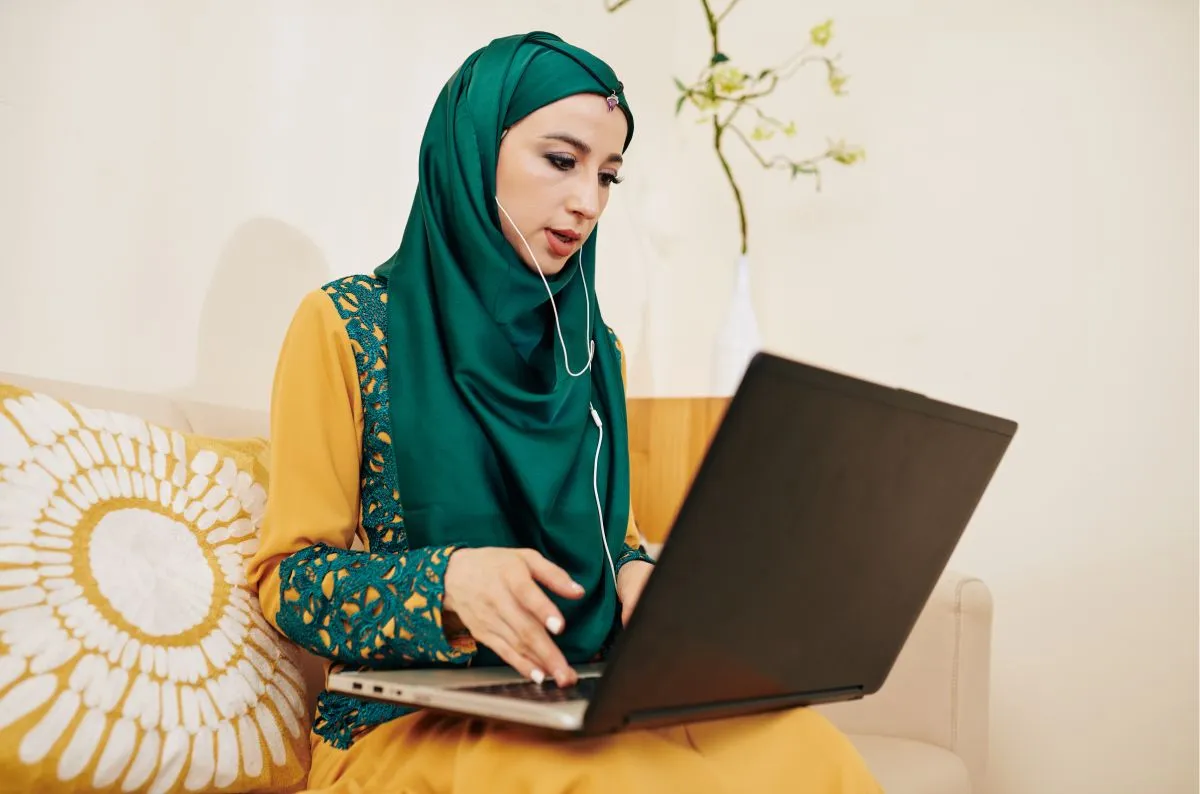 Muslim woman attending a private online Quran lesson on a laptop at home
