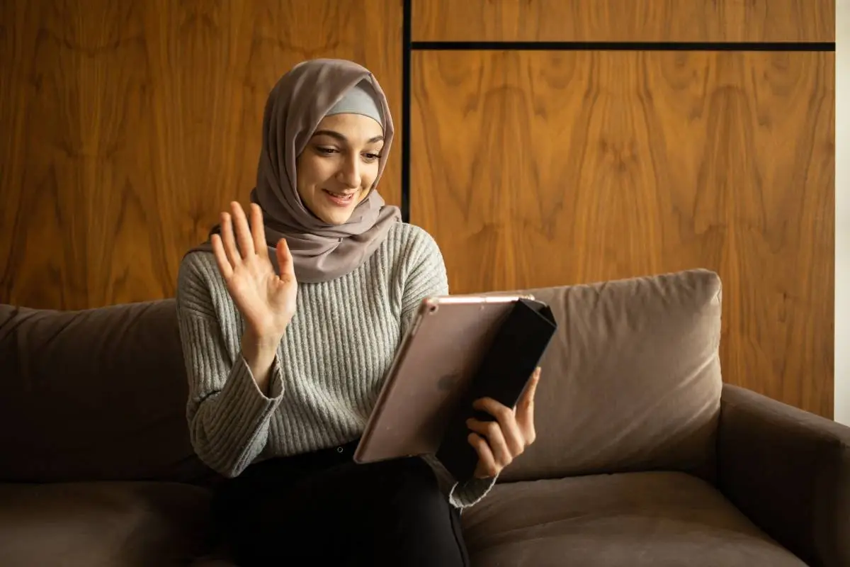 Muslim woman attending a live online Quran Tafseer class on a tablet