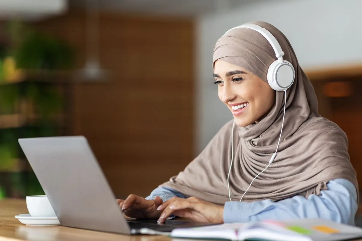 Muslim woman wearing headphones during a private online Quran lesson