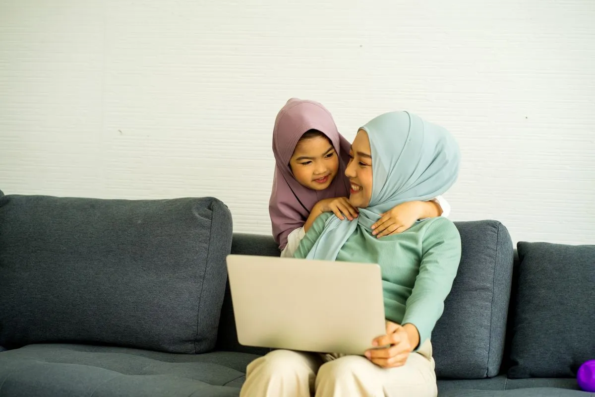 Mother and daughter sitting together with a laptop on a sofa at home