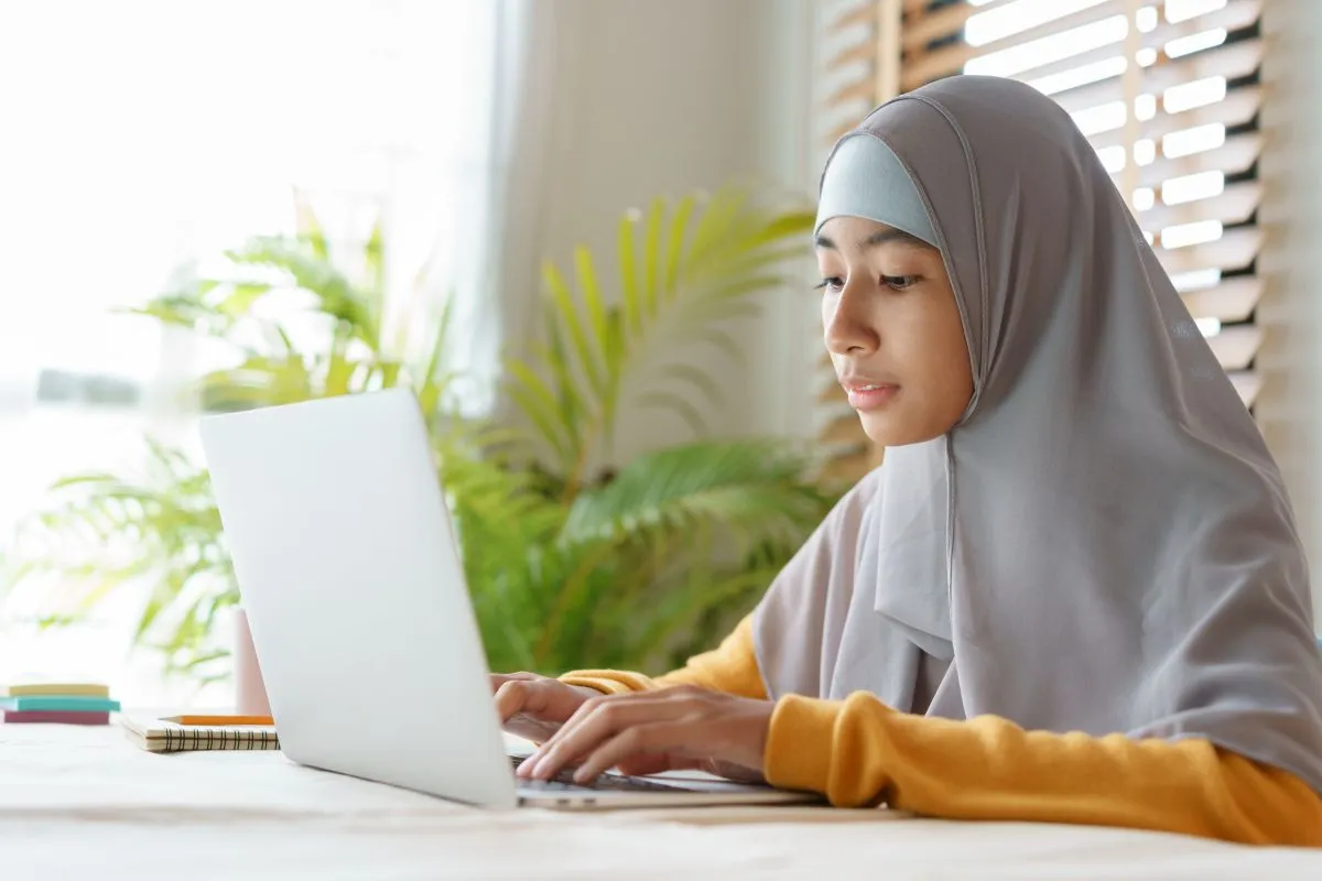 Young Muslim student attending an online Quran class on a laptop at home