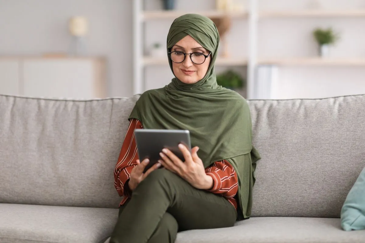 Woman in a green hijab attending an online Quran memorization lesson