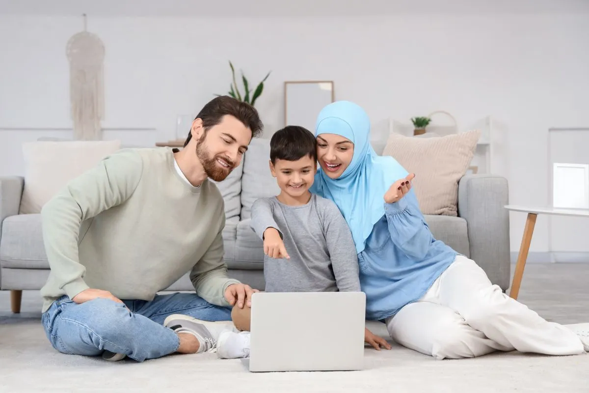 Parents supporting their son during an online lesson on a laptop at home