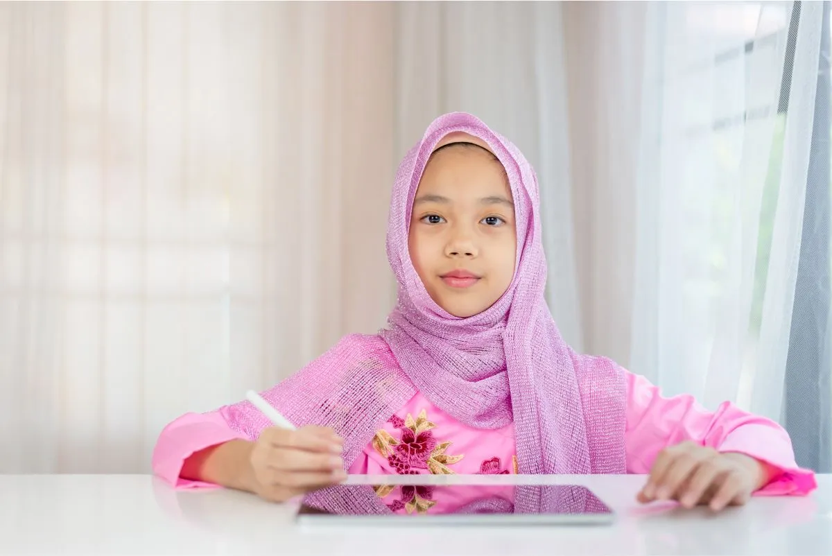 Young Muslim girl studying during a private online Quran lesson at home
