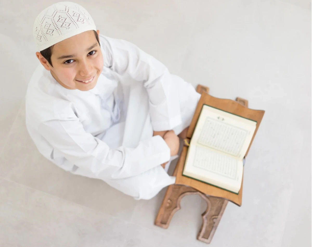 Young Muslim student reading the Quran from a wooden stand