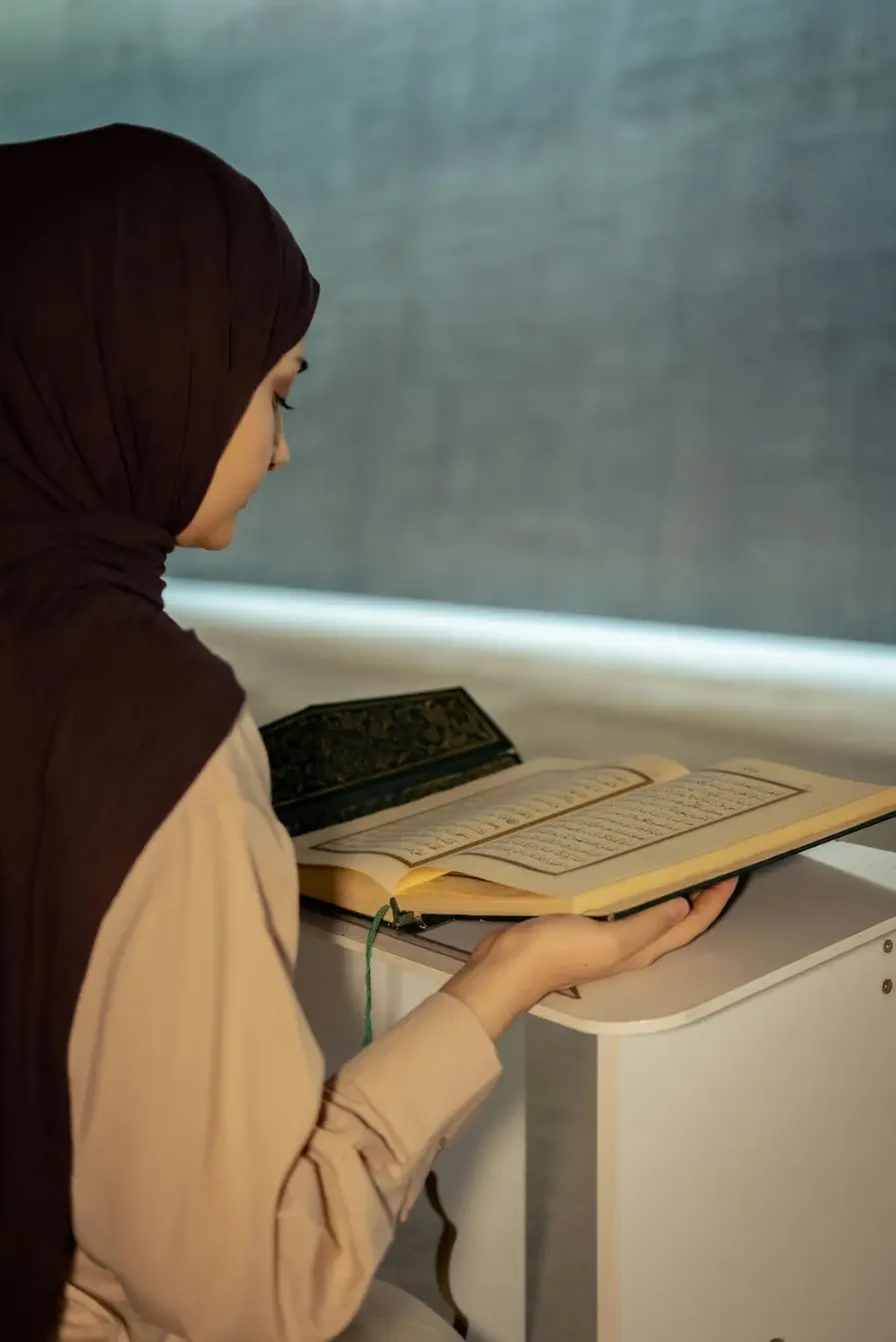 Muslim woman reading an open Quran during a home study session